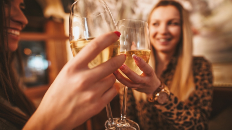 Dve žene nazdravljaju čašama belog vina na vinskoj degustaciji