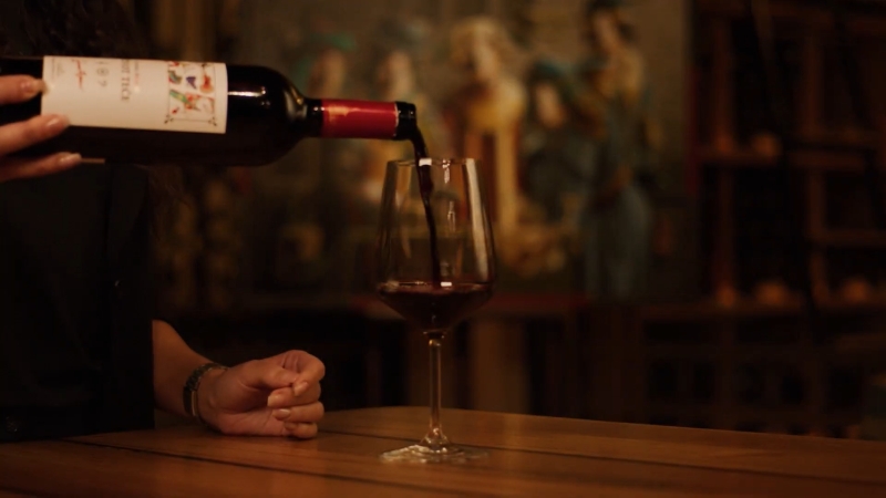 Crveno vino se sipa u čašu u ambijentu vinskog podruma