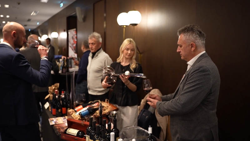 Posetioci degustiraju crveno vino za štandom na vinskom festivalu